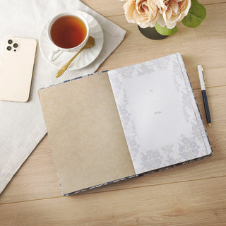 Open devotional journal with floral interior showing To/From gift page, styled with tea and pen