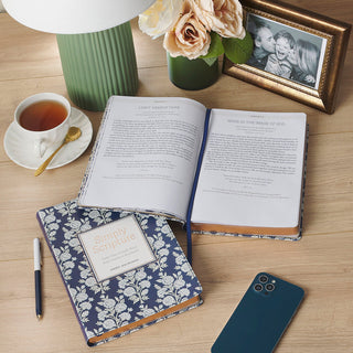 Simply Scripture devotional book open and closed showing navy floral faux leather cover on wooden desk