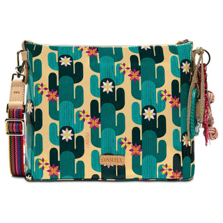 Back of Consuela Dezi crossbody with teal cactus pattern, leather brand plaque, and decorative tassel charm