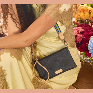 Black glitter woven crossbody bag with tan leather trim and rainbow strap worn with yellow lace dress