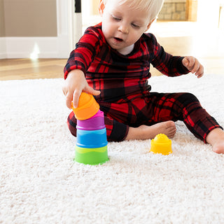Baby playing with Fat Brain Toys Dimpl Stack colorful stacking cups on white carpet