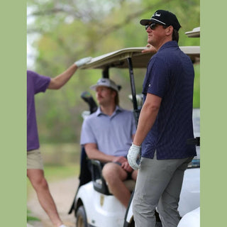 Golfers on a golf course with one getting ready to hit the ball.