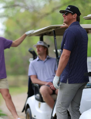 Golfers on a golf course with one getting ready to hit the ball.