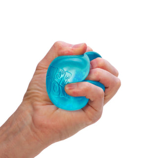 Hand squeezing a translucent blue Dream Drop Needoh stress ball toy against white background