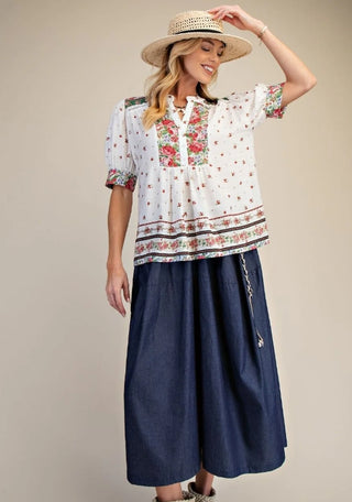 Woman wearing a patterned blouse and navy skirt 