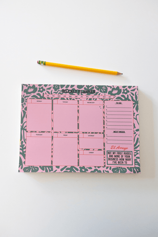 El Arroyo pink weekly planner with green floral border and humorous quote block