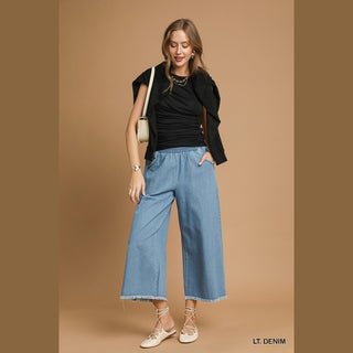 Light wash women's wide-leg denim culottes styled with black top and mules