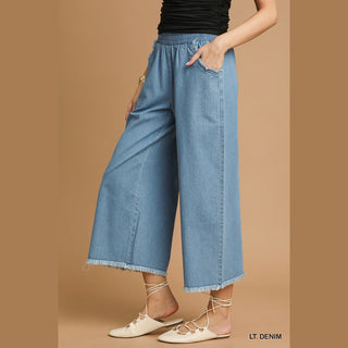 Light blue relaxed fit wide-leg denim pants showing side profile drape and fringe hem