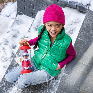 Child holding Elf on the Shelf Scout Elf Carrier lantern outdoors in snow