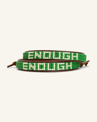 Green and white beaded leather wrap bracelet spelling ENOUGH on neutral background