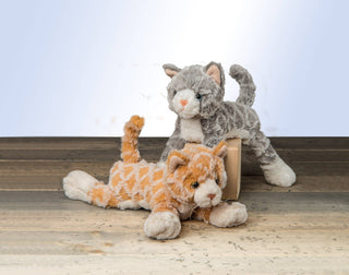 Two plush cat stuffed animals, orange tabby and gray tabby kittens, on wood floor