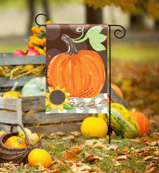 Demdaco fall pumpkin garden flag displayed outdoors on black metal stand among autumn gourds