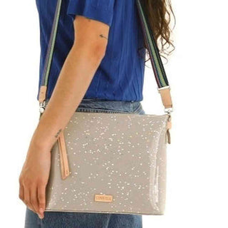 Person holding a beige crossbody bag with star patterns 