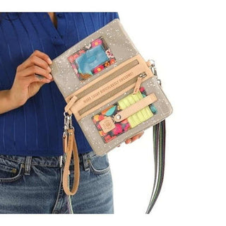 Person holding a colorful handbag with floral patterns and text 