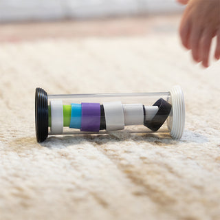 Fat Brain Toys Flipty clear tube toy with colorful spinning discs on carpet