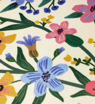 Close-up detail of floral pillow fabric with pink, blue, yellow flowers on cream background
