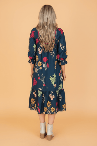 Navy floral midi dress with puff sleeves, tiered ruffle hem, worn with cream boots