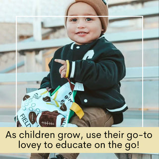 Toddler in stadium bleachers holding football field patterned baby lovey with yard lines