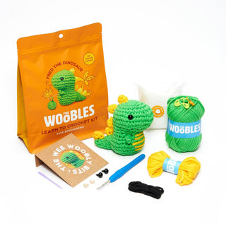 Woobles Fred the Dinosaur beginner crochet kit with green yarn, hook, and finished amigurumi plush