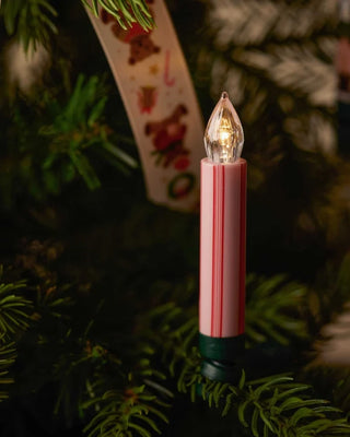 Pink and red striped clip-on candle light glowing on a Christmas tree branch