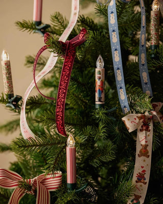 Red and white striped clip-on candle lights decorating a green Christmas tree with ribbons