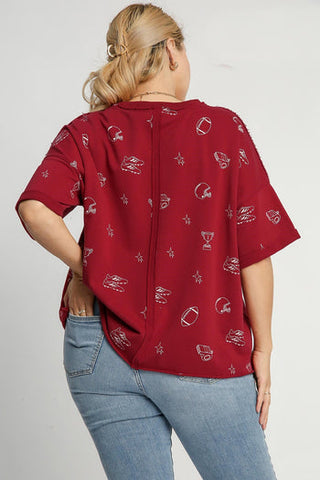 Back view of wine-colored French terry top with football-themed print on female model