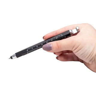 Hand holding black hexagonal multi-tool pen demonstrating ergonomic grip size