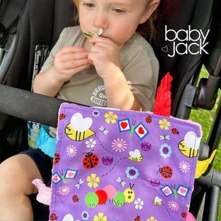 Purple baby lovey hanging from stroller handlebar with garden insect print