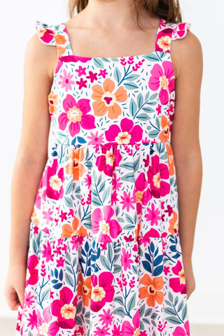 Child wearing a floral dress with pink, orange, and blue flowers 