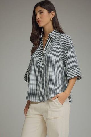 Side close-up navy gingham blouse highlighting crinkled fabric drape and gold jewelry styling