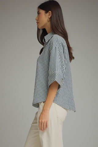 Side profile of relaxed fit navy gingham blouse styled with cream wide-leg trousers