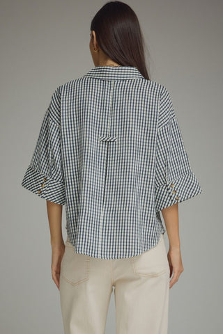 Back view navy gingham blouse with curved hem, brown buttons, and cotton-poly blend texture