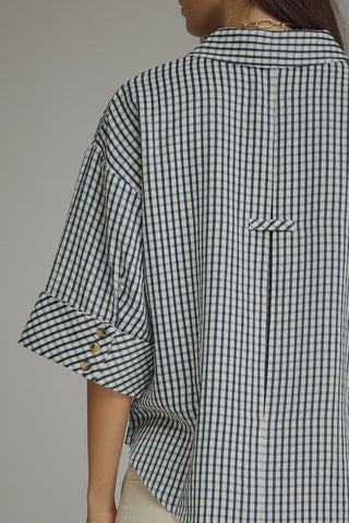 Back view navy gingham blouse featuring center seam, waist pocket, and buttoned 3/4 sleeves