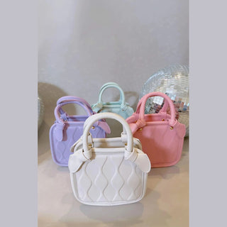 White girl's retro wavy quilted handbag with gold hardware and bow accents in group display