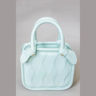 Close-up mint green children's wavy quilted vegan leather purse with structured shape and side bows