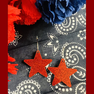 Red glitter star hoop earrings with silver hooks on navy paisley fabric