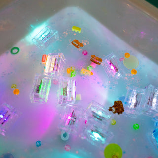 Glo Pals light-up clear sensory cubes glowing in colorful water with small toy figurines