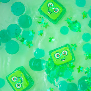 Glo Pals Pippa green light-up sensory cubes floating in water with green confetti and discs