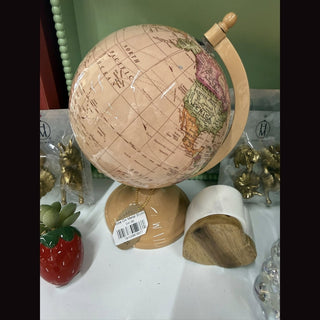 Globe on metal stand with beige enameled plastic sphere, green North America map, light wood meridian arm, and matte tan ceramic base