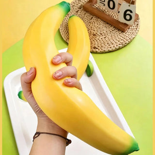 Two bright yellow banana squishies held side by side on lime green table