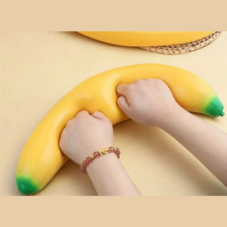 Hands squeezing soft slow rise foam banana squishy showing deformation and texture