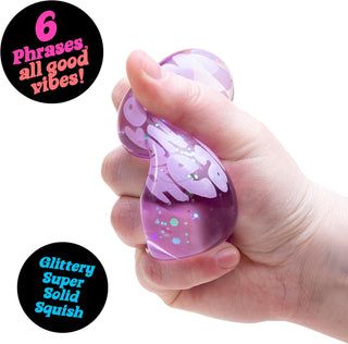 Purple NeeDoh solid-squish heart toy being squeezed to show flexible texture and embedded sparkle