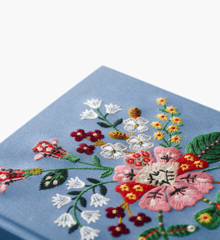 Close-up detail of colorful floral embroidery on blue fabric cover of Gracie Sketchbook