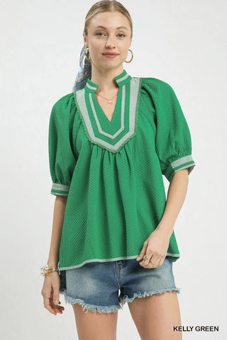 Woman wearing a green blouse with white trim
