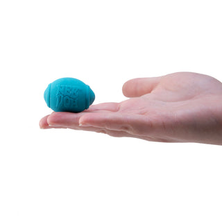 A hand holding a small teal Nee Doh stress ball shaped like a miniature football