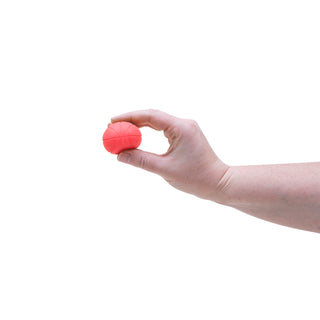 Hand holding a small coral-colored Teenie Needoh stress ball with basketball texture pattern