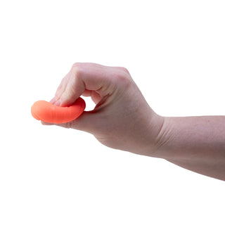 Hand squeezing a small coral-orange Teenie Needoh sensory stress ball toy