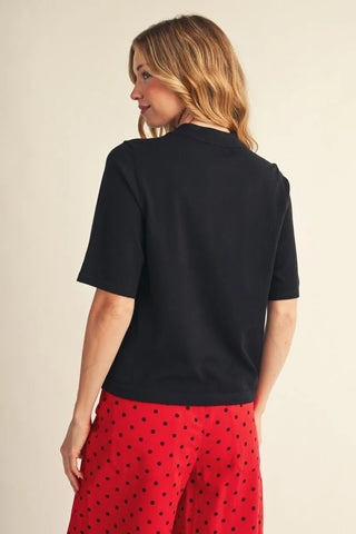 Black half sleeve sweater top, back view, paired with red polka dot skirt