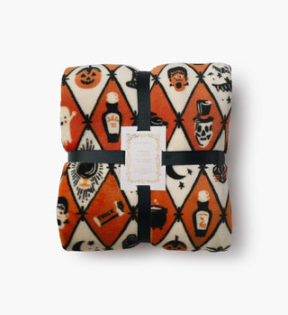 Rifle Paper Co. Halloween argyle fleece blanket folded and tied with black ribbon, featuring spooky motifs.