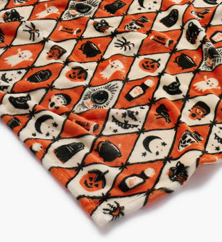 Close-up detail of Halloween argyle fleece blanket with orange and cream diamond pattern featuring spooky motifs